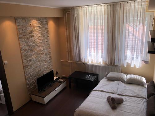 a bedroom with a bed and a television and a brick wall at Balian apartman in Siófok