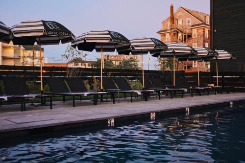 a row of chairs with umbrellas next to a swimming pool at Lokal Hotel Cape May in Cape May