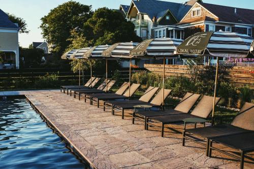 a row of lounge chairs with umbrellas next to a pool at Lokal Hotel Cape May in Cape May