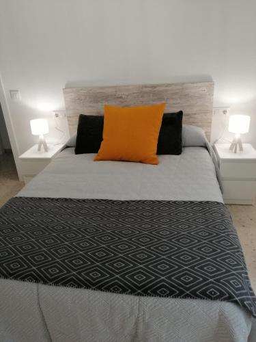 an orange pillow on a bed with two lamps at Sueños Mozárabes in Córdoba