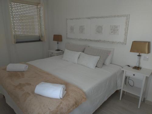 ein weißes Schlafzimmer mit einem großen Bett mit weißer Bettwäsche und Kissen in der Unterkunft Casa da avó Lu in Olhão