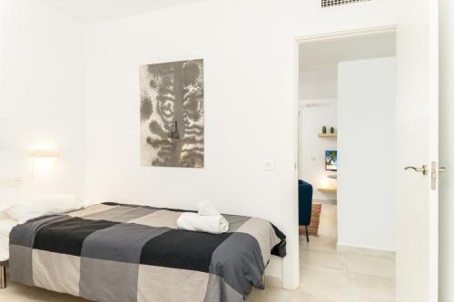 マラガにあるSuite Homes La Victoriaの白いベッドルーム(ベッド1台付)が備わります。壁には絵画が飾られています。