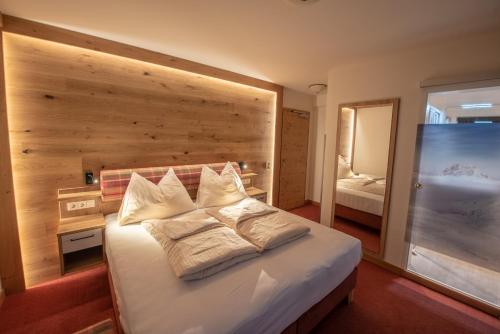 sypialnia z dużym łóżkiem i drewnianą ścianą w obiekcie Hölzl Bed & Breakfast w mieście Neukirchen am Großvenediger