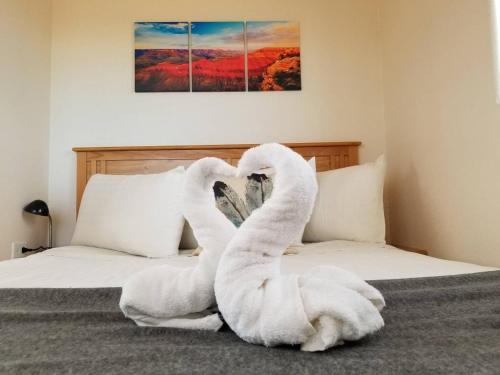 ヴァジェにある072A Affordable Getaway near South Rim Sleeps 4- No Kitchenetteのベッドに座るタオルで作られた白鳥2羽