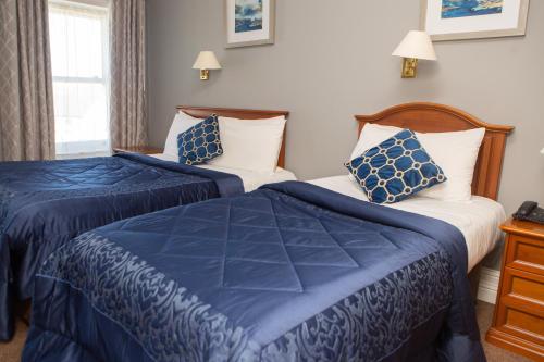 two beds in a hotel room with blue and white sheets at Leens Hotel in Abbeyfeale