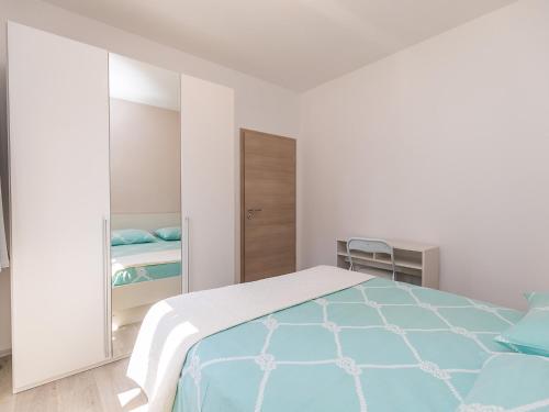 a white bedroom with a bed and a mirror at Apartment Stefano - free wine&spirit tasting in Višnjan