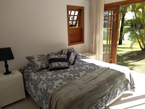 a bedroom with a bed with pillows and a window at PRAIA DO FORTE - CONDOMINIO VILLAGE DAS ACACIAS - PISCINAS NATURAIS in Praia do Forte