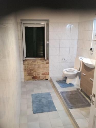 a bathroom with a toilet and a window and blue rugs at RIVER HOUSE MARIA in Lefkimmi