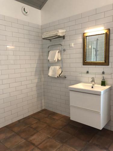 a white bathroom with a sink and a mirror at Nedanby | Cottage | Idyllic location | Porch | Grill in Edsbro