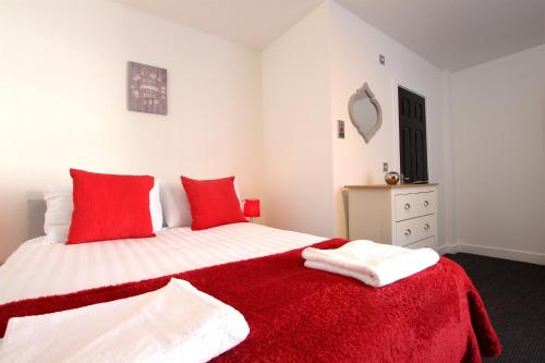 een slaapkamer met een bed met rode kussens en een rode deken bij Blackpool Tower Apartments by Blackpool Service Aparttments in Blackpool