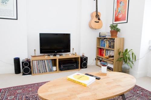 uma sala de estar com uma mesa e uma televisão em Bright 2 bedroom Apt - Great location - Free Parking em Bournemouth