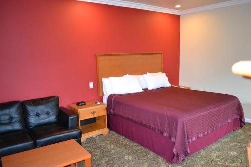 a hotel room with a bed and a leather chair at The Miramar Inn in Half Moon Bay