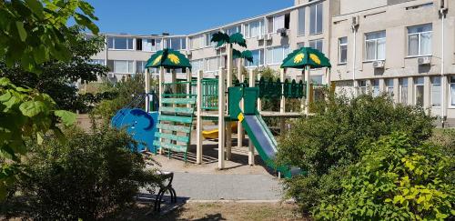 a playground with a slide and umbrellas in front of a building at Апартаменти перша лінія Затока Променад in Zatoka