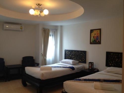 a bedroom with two beds and a window at Wangburapa Grand Hotel in Chiang Mai
