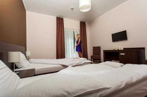 a woman looking out the window of a hotel room at Hotel & Spa Polesie in Białka