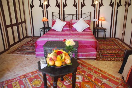 a bedroom with a bed with a bowl of fruit on a table at Hotel Dar Zitoune Taroudant in Taroudant