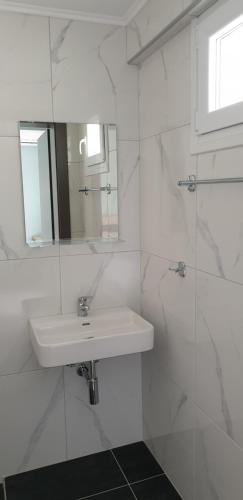 a white bathroom with a sink and a mirror at Chriselia 1 in Nea Roda