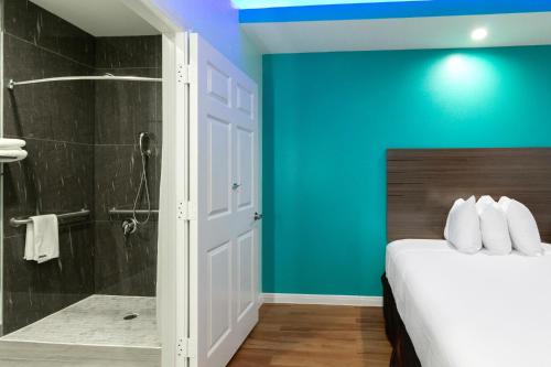 ein Schlafzimmer mit einer blauen Wand, einem Bett und einer Dusche in der Unterkunft Americas Best Value Inn- Aldine Westfield in Humble