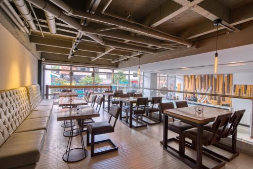 a restaurant with wooden tables and chairs and windows at Hotel Dix in Medellín