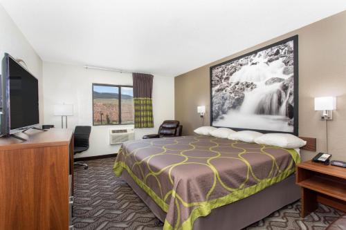 a hotel room with a bed and a flat screen tv at Super 8 by Wyndham Dubois in Dubois