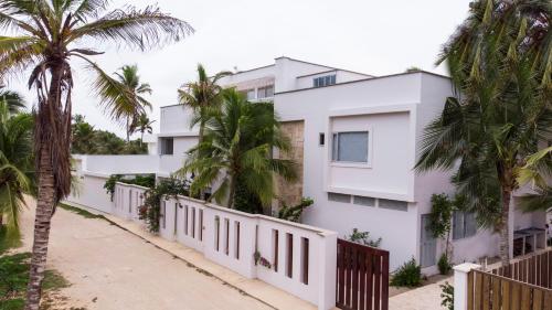 a white house with palm trees in front of it at Hotel Rilux Tolu in Tolú