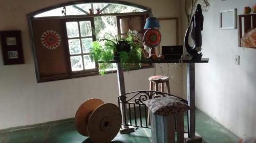 a room with a window and a table with stools at Hospedaria Alecrim - Pousada Sustentável APA in Petrópolis