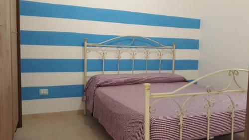 1 dormitorio con 1 cama con rayas azules y blancas en Villino Celeste fronte spiaggia, en Torre Lapillo