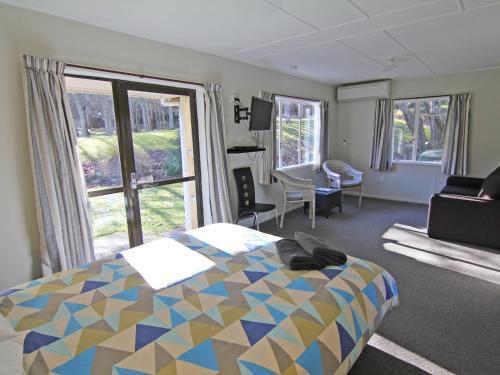 a bedroom with a bed and a large window at Alpine Adventure Holiday Park in Hanmer Springs