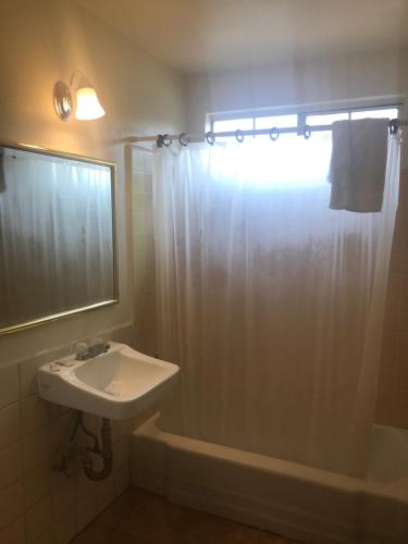 a bathroom with a sink and a shower with a shower curtain at All 8 Motel in Long Beach