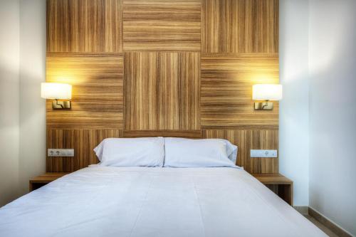 a bedroom with a bed with two lights on the wall at Apartaments Lauria in Tarragona