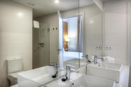 a bathroom with two sinks and a toilet and a mirror at Apartaments Lauria in Tarragona
