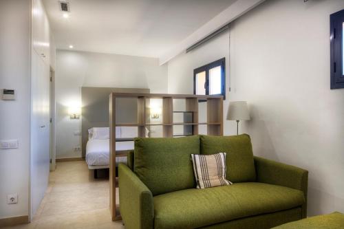 a living room with a green chair and a bed at Apartaments Lauria in Tarragona