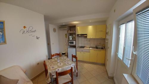 cocina con mesa y cocina pequeña con armarios amarillos en Apartments Nadica - free parking, en Nin