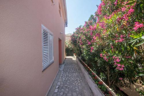 an alley between two buildings with pink flowers at Apartment and Rooms Amenka in Novalja