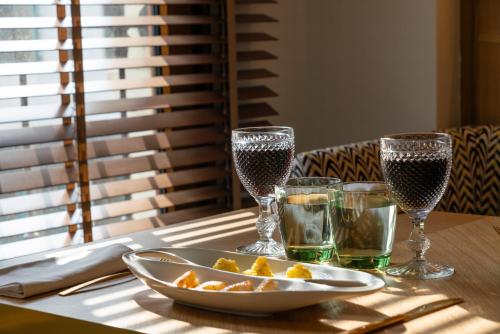 a table with glasses of wine and a plate of food at Puente Colgante Boutique Hotel in Portugalete