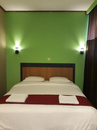 a bedroom with a large bed with a green wall at The New Orlinds Guest House in Wonosari