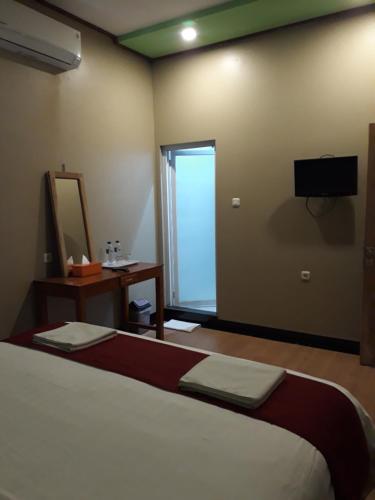 a bedroom with a bed and a mirror and a television at The New Orlinds Guest House in Wonosari