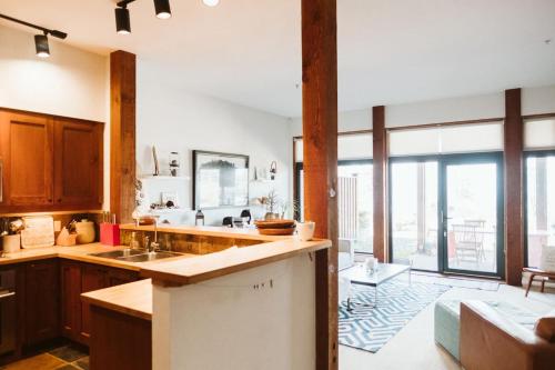 uma cozinha com armários de madeira e uma grande janela em Pacific Soul Eco-Luxe Vacation Home em Ucluelet