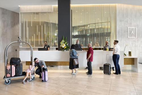 ブリスベンにあるAlcyone Hotel Residencesの空港で荷物を持って待つ人々