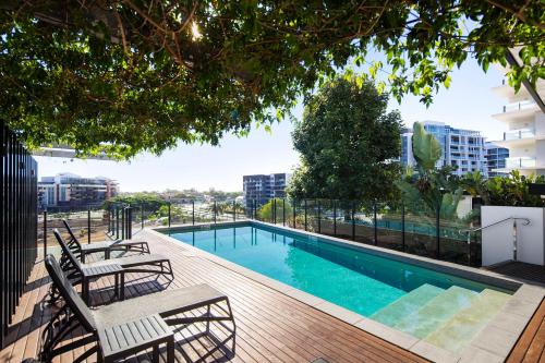 a swimming pool on a deck with chairs and a building at Alcyone Hotel Residences in Brisbane
