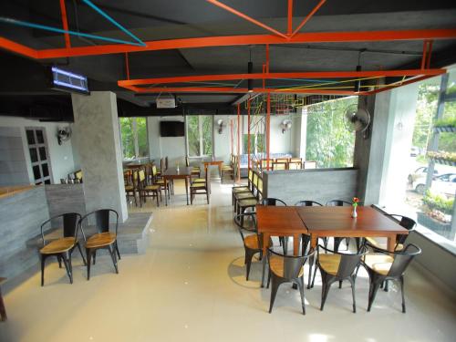 a restaurant with wooden tables and chairs and windows at WithInn Hotel - Kannur Airport in Kannur