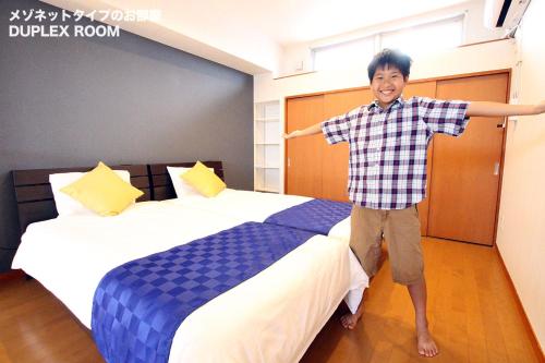 a young boy standing on a bed in a hotel room at Chura Minpaku Ishigaki in Ishigaki Island