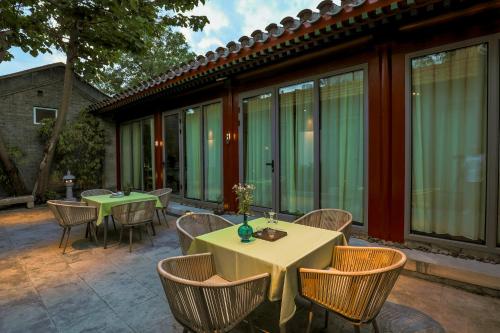 a patio with two tables and chairs and windows at Beijing Heyuan Courtyard Hotel (Forbidden City) in Beijing