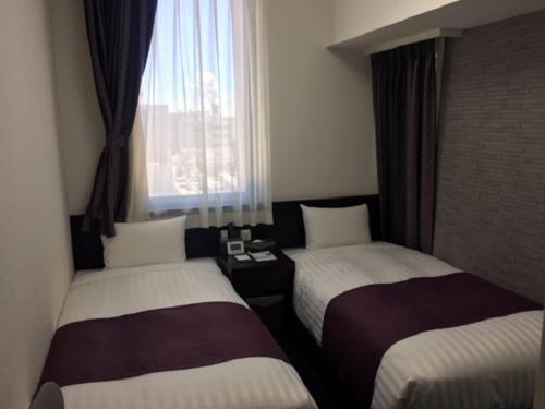 a hotel room with two beds and a window at Ueno Urban Hotel in Tokyo