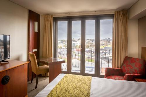 a hotel room with a bed and a desk and a window at Copthorne Hotel Auckland City in Auckland