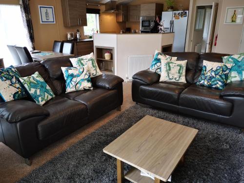 a living room with two leather couches and a coffee table at Trevellian - Spacious Scenic Lodge - Tranquil Retreat in Dawlish