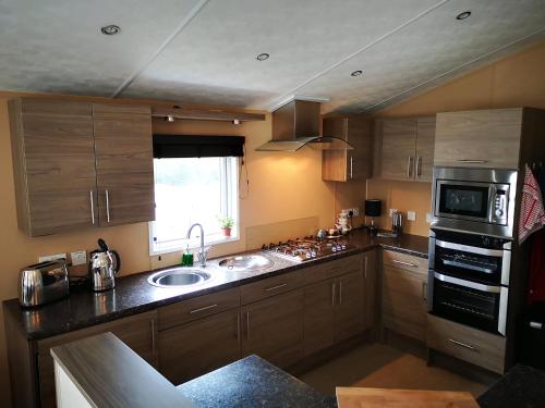 a kitchen with wooden cabinets and a sink and a window at Trevellian - Spacious Scenic Lodge - Tranquil Retreat in Dawlish