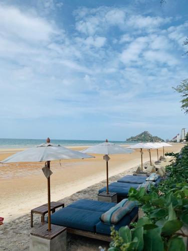 a row of beach umbrellas on a sandy beach at Let's Sea Hua Hin Al Fresco Resort in Hua Hin
