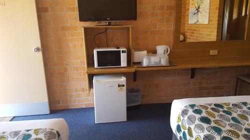 Habitación con nevera pequeña y microondas. en Royal Palms Motor Inn, en Coffs Harbour