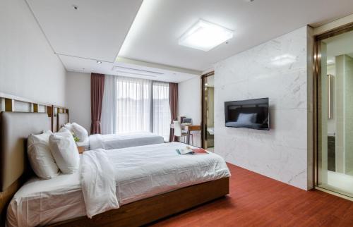 pokój hotelowy z łóżkiem i telewizorem w obiekcie Seaside Arden w mieście Seogwipo